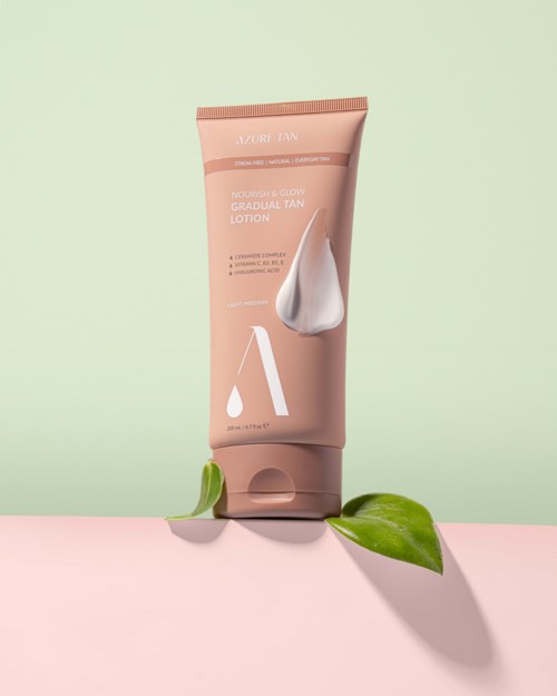 Eine rosa Lotion auf einer zweifarbigen Oberfläche mit einem Blatt, fördert allmähliche Bräune und Glanz.
