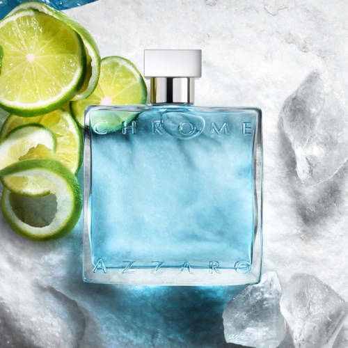 Een blauw parfumflesje met GHROME AZZARO, omgeven door limoenpartjes en ijsblokjes.