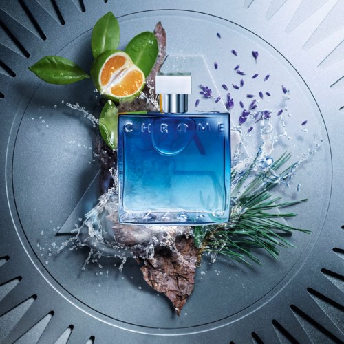 Een blauw parfumflesje met groene bladeren, een sinaasappelschijf en paarse bloemen in een wasbak.