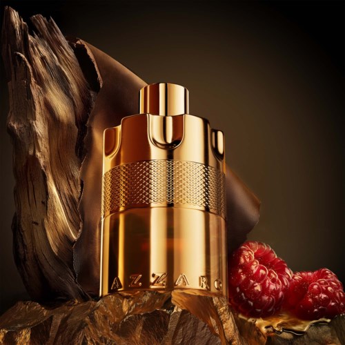 Een gouden parfumfles met een getextureerd band staat naast hout en bessen, zacht verlicht op een donkere achtergrond.