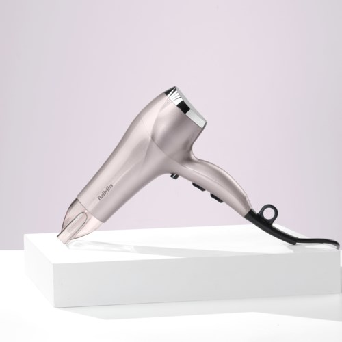 A hair dryer with a silver and black design on a white surface and plain background.