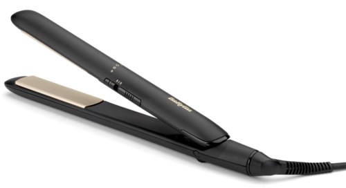 A black electric hair straightener with a gold plate, placed on a black surface.