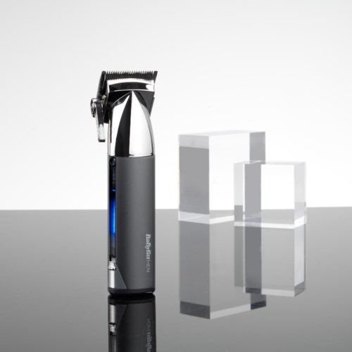 A hair clipper stands on a reflective surface with three white geometric blocks behind it.