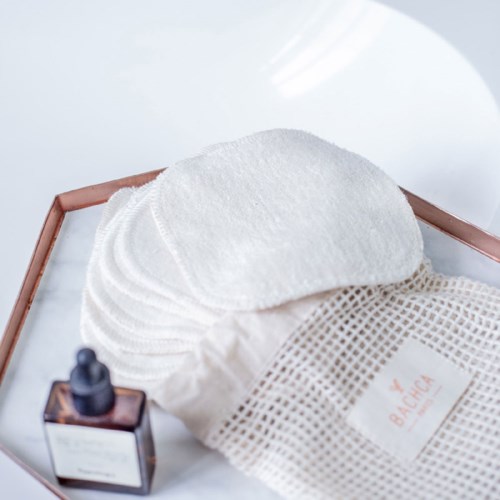 Cotton pads, a bottle, and a cotton pouch on a tray, likely for skincare or facial use.