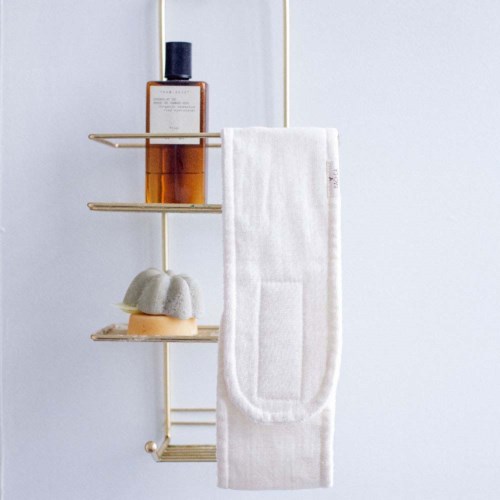 A bathroom shelf holds a brown bottle, a white towel, and a white soap bar.