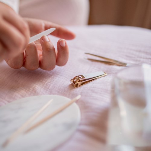 A person prepares to take a sample with a small spatula, with beauty tools and a cloth on the table.