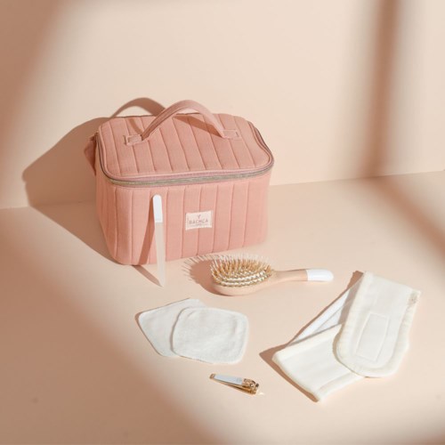 Pink bag, hairbrush, cloth, clips, and hair towel on a light table surface.