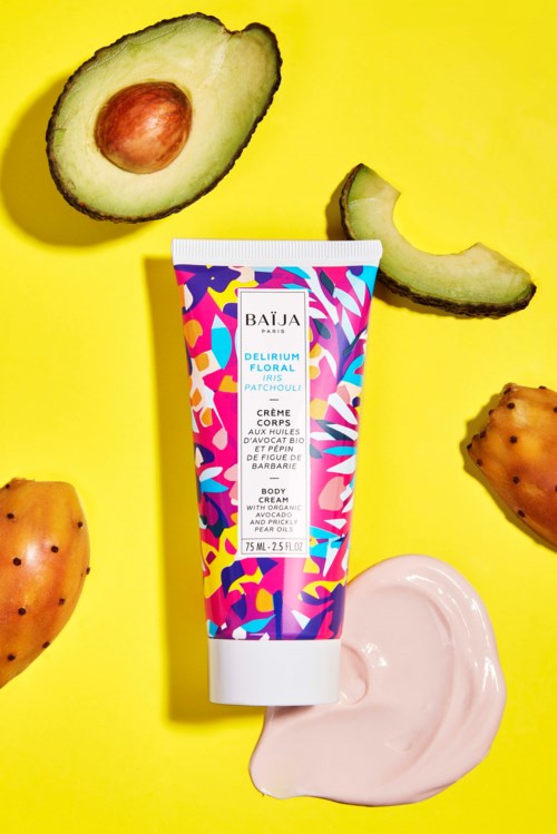 Body cream tube surrounded by avocado, prickly pear, and a pink cream on yellow background.