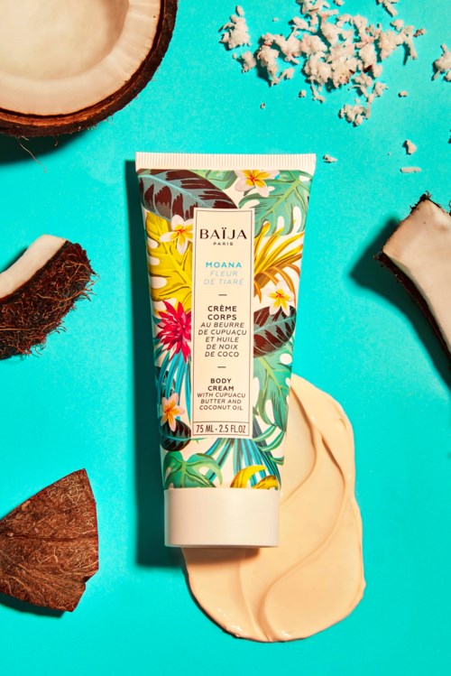 A tropical face cream tube surrounded by coconut, coconut shell, and natural ingredients on a bright blue background.