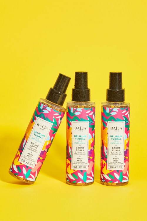 Three colorful spray bottles with floral labels stand on a yellow background.