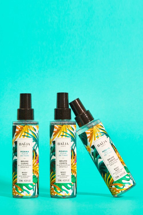 Three bottles of body spray with colorful leaf patterns, against a blue background, one tilted.