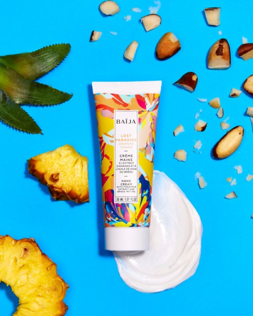Colorful hand cream tube with pineapple, nuts, and green leaf on blue background.