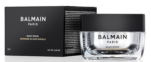 En svart låda och tydlig burk med vit kräm, båda märkta Balmain Paris Scalp Scrub för hår.