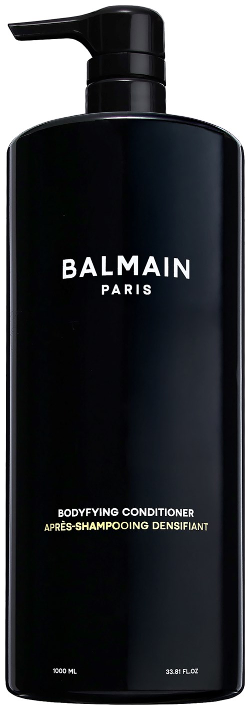 Pitkä musta pullohylsy, jossa pumppu, nimeltä Balmain Paris, vartalonhoitoon.