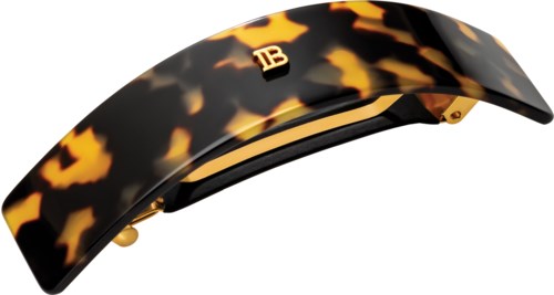 A tortoise shell patterned hair clip with gold accents and a small logo.