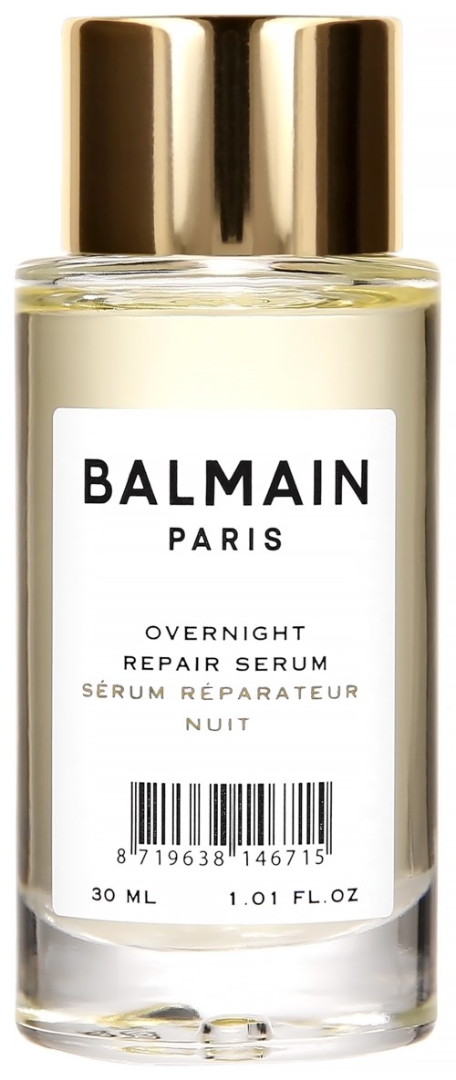Läpinäkyvä lasipullo, kultainen kansi ja valkoinen tarra, sisältää Balmain Parisin yönkorjausseerumin.