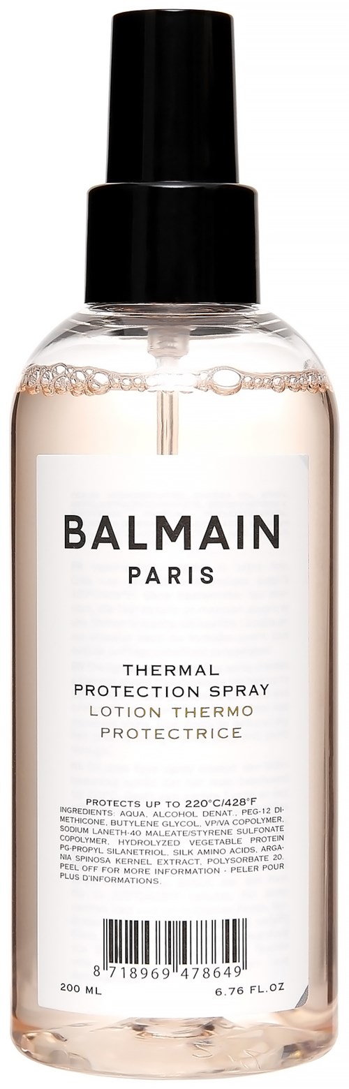 Lähes läpinäkyvä suihkepullo, jossa musta suihkepää ja valkoinen etiketti, sisältää lämpösuojaa Balmain Parisilta.