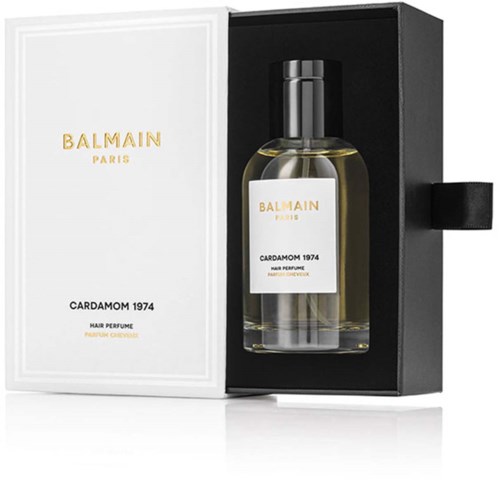 En gjennomsiktig flaske med gul væske, merket Balmain Paris Cardamom 1974, i en svart boks med hvit og gulltekst.