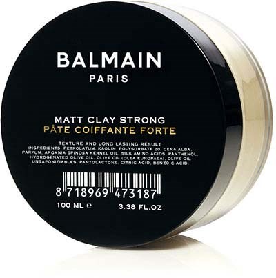 A round container with black lid, contains Balmain Paris hair clay, labeled with product details and ingredients.