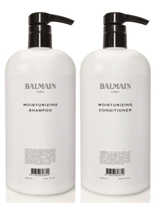 Kaksi valkoista pulloa, joissa on mustat pumppunkit ja lukee 'Balmain Paris.' Toisessa on shampoo ja toisessa hoitoaine.