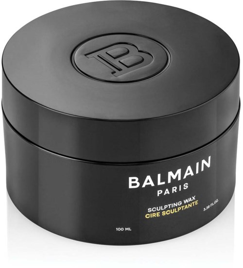 En svart rund beholder med lokk, merket 'Balmain Paris Sculpting Wax.' Den inneholder 100 ml voks.