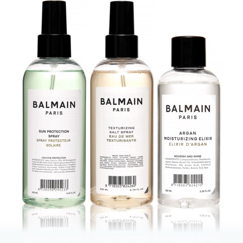 Tre flaskor med Balmain hudvårdsprodukter med svarta lock, märkta för solskydd, saltspray och fuktighetskräm.
