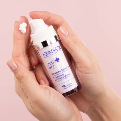 En hand håller en vit flaska med hudvårdskräm med pump, märkt 'anti dry' och 'nourishing and moisturizing'.