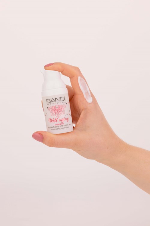 Eine Hand hält eine kleine weiße Flasche mit einem pinkfarbenen Etikett, das "Well aging" sagt, und einem Pumpkopf.