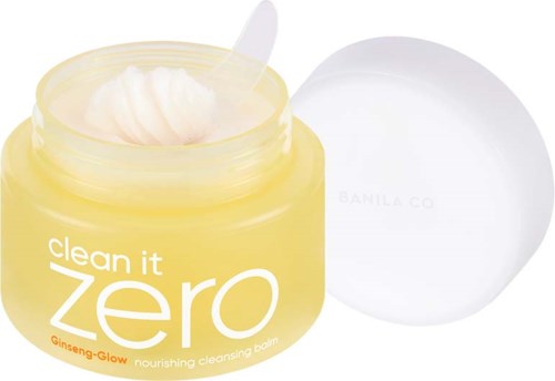 Ein gelber Behälter mit "Clean It Zero" enthält eine nährende Reinigungsbalsam, mit einem kleinen Spatel und einem weißen Deckel.