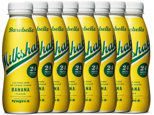 Row of seven yellow bottles labeled 'Waldsah Milkshakes' with banana flavor, 24 grams protein, lactose free, no added sugar.