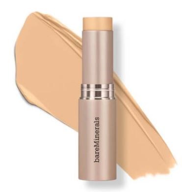 En beige foundation-sticka med ett prov bakom. Produkten har en beige lock och en silverrand.