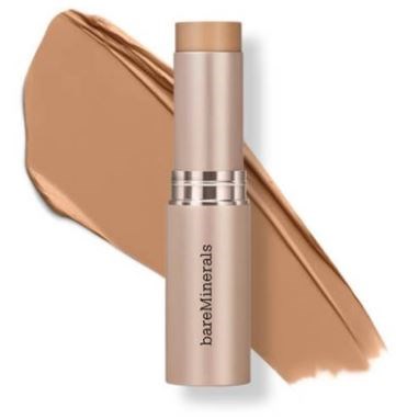 Ett beige concealer-påssticke med en silverring, placerad på ett ljusbrunt smink.
