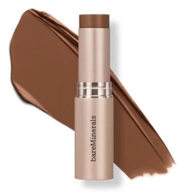 En beige sminkstift med brun kork står framför ett svep av brunt smink. BareMinerals står på stiftet.