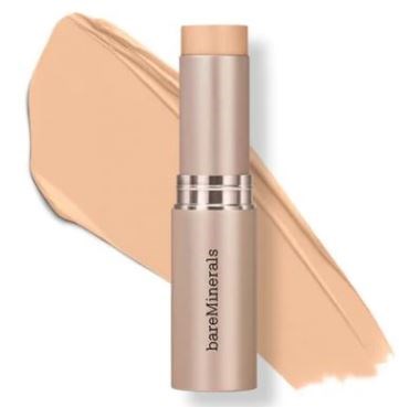 En beige stav med silverband, märkt 'bareMinerals', bredvid en smet av beige foundation.
