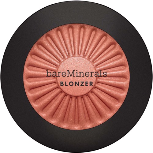 A round makeup blush with a black outer case and pinkish powder in the shape of a flower or sunburst. Contains text.