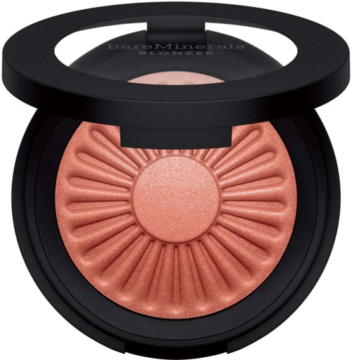 A round blush compact with a black lid, featuring a peachy-pink shimmery blush with embossed rays design.