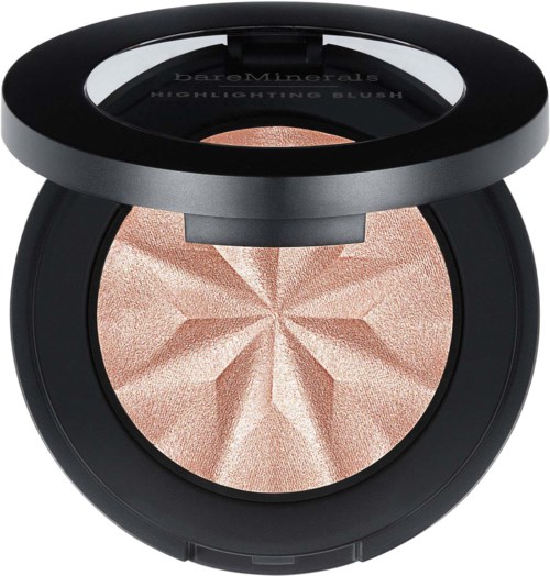 A round makeup compact with a raised star-shaped design in light pink, and a black lid with words. 