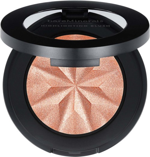 A compact makeup highlighter with a pressed peachy shimmer design inside a round black case.
