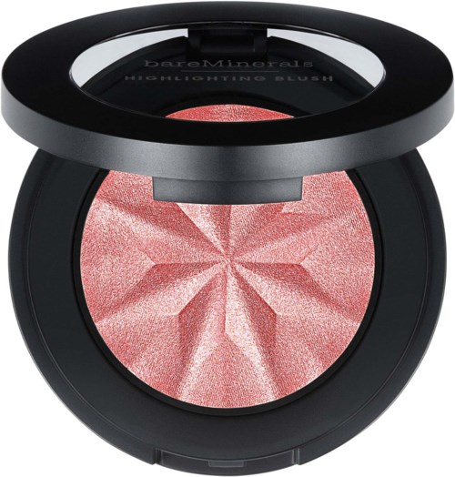 A pink blush with a star-like pattern inside a round black compact with a mirror.