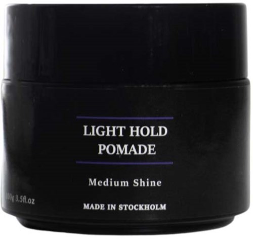 A black jar labeled 'Light Hold Pomade, Medium Shine, Made in Stockholm,' likely used for hair styling.