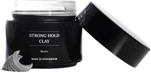 A black jar labeled "Strong Hold Clay" with a lid, and a dollop of gray clay comes out of it.