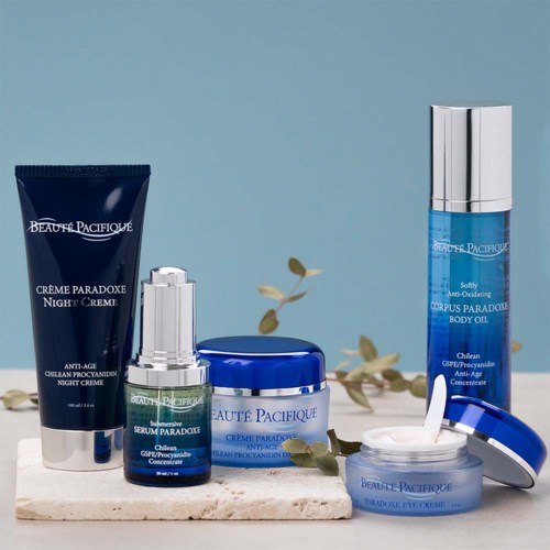 Verzameling huidverzorgingsproducten in blauwe verpakking, waaronder crèmes, serum en olie, op een lichte ondergrond.