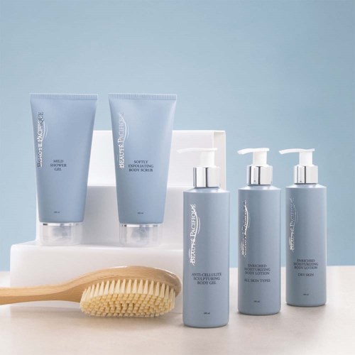 A set of skincare products in blue bottles and tubes, with a brush and white tray in the background.