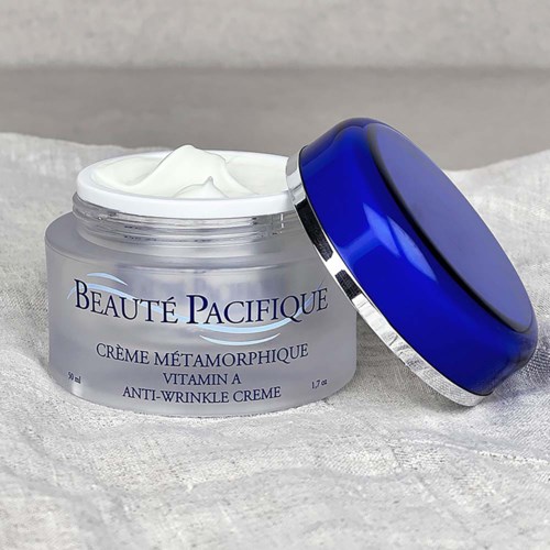 Een potje anti-rimpelcrème met label 'Beauté Pacifique' en een blauwe deksel, gedeeltelijk open op een getextureerd oppervlak.