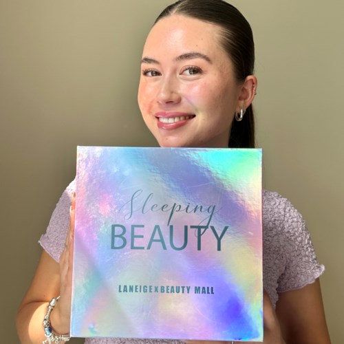Een lachende vrouw houdt een holografische doos met 'Sleeping Beauty' van LaneigexBeauty Mall.