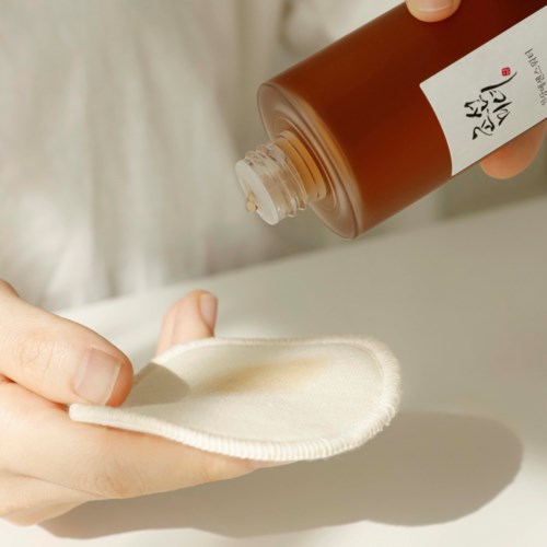 Iemand giet vloeistof op een doekje, waarschijnlijk om een product aan te brengen. Close-up, eenvoudig.