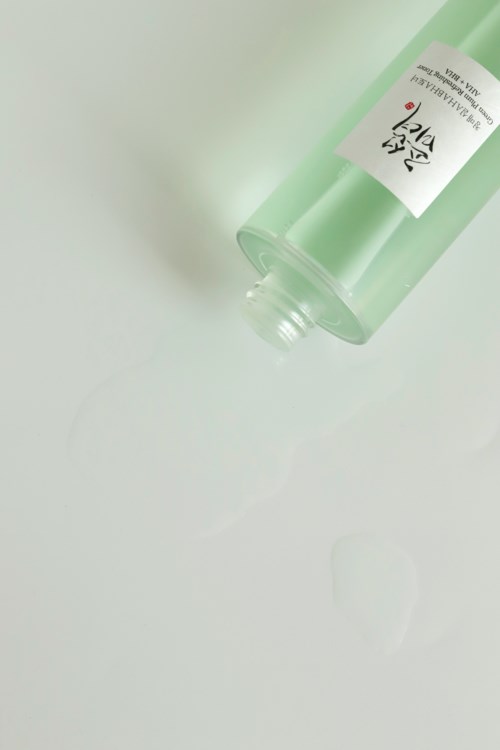 A light green bottle with a white label, lying on its side on a light surface.