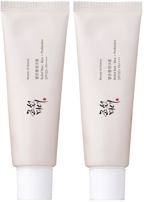 Two white tubes with black and red writing, likely skincare or cosmetic products, standing upright.