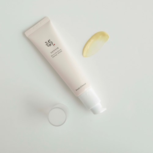 A white tube with Korean writing, a small sample smear, and an open cap on a white surface.