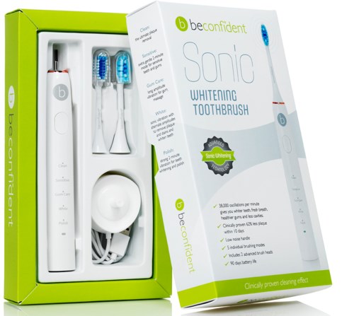 A white electric toothbrush with a charging base, two brush heads, and green packaging that highlights whitening benefits.
